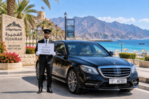 Chauffeur service Fujairah – luxury sedan with coastline and mountain backdrop